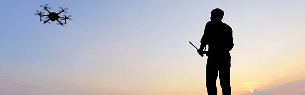 istock man operating of flying drone multicopter UAV at sunset 607605202