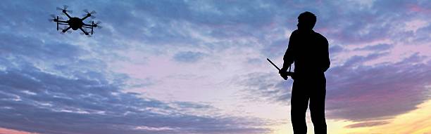 istock man operating of flying drone multicopter UAV at sunset 607605274