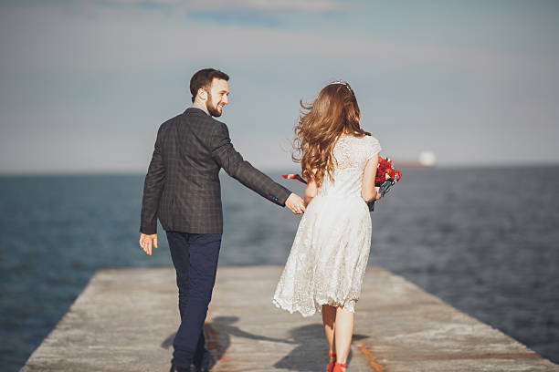 istock Married wedding couple standing on a wharf over the sea 607605366