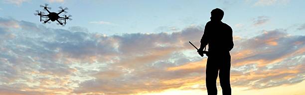 istock man operating of flying drone multicopter UAV at sunset 607605384