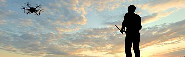 istock man operating of flying drone multicopter UAV at sunset 607605444