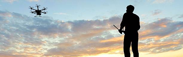 istock man operating of flying drone multicopter UAV at sunset 607605634