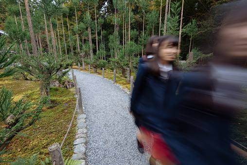 Kyoto, Japan - Nov 7, 2015: Students walking in the garden of the Ryoan-ji Temple in Kyoto, Japan. Long exposure blur effect. 
