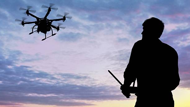 istock man operating of flying drone multicopter UAV at sunset 607606656