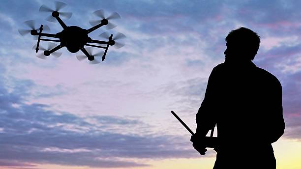 istock man operating of flying drone multicopter UAV at sunset 607606738
