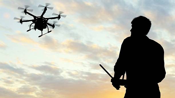 istock man operating of flying drone multicopter UAV at sunset 607606926