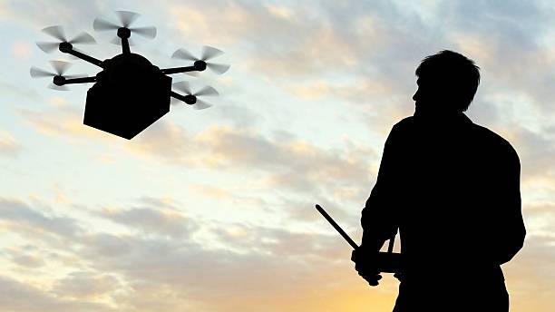 istock man operating of flying drone multicopter UAV at sunset 607607026