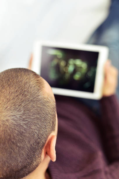a young caucasian man lying on the couch watches a movie or a series in streaming in his tablet computer