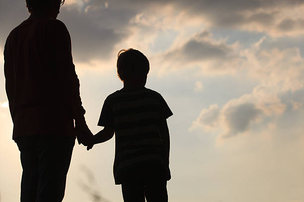 istock silhouette of father and son holding hands at sunset 607608604