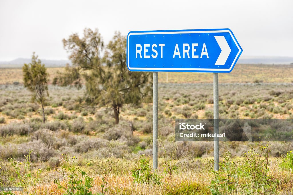 Blue rest area sign Blue rest area sign on side of road with grey sky and green vegetation Rest Area Stock Photo