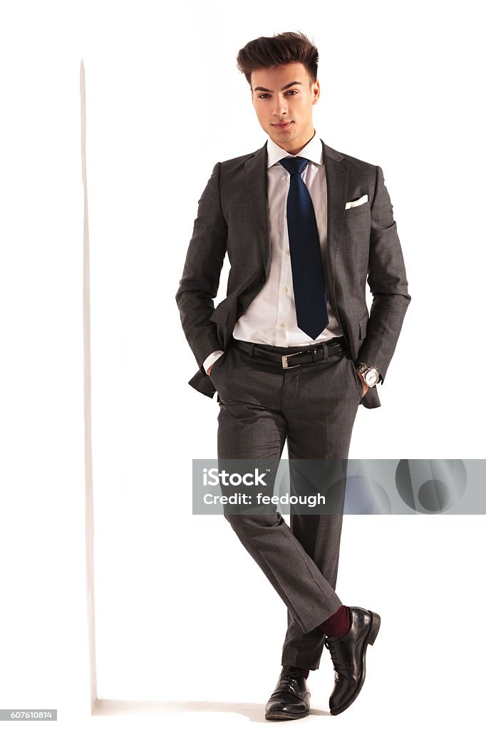 sexy young business man with hands in pockets sexy young business man with hands in pockets standing near wall in studio Adult Stock Photo