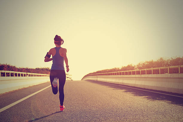 istock young woman runner running on city bridge road 607611178