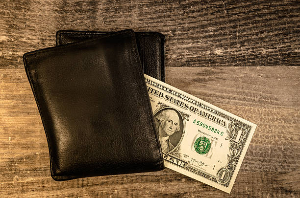 US dollar bills coming out of wallet on white background.