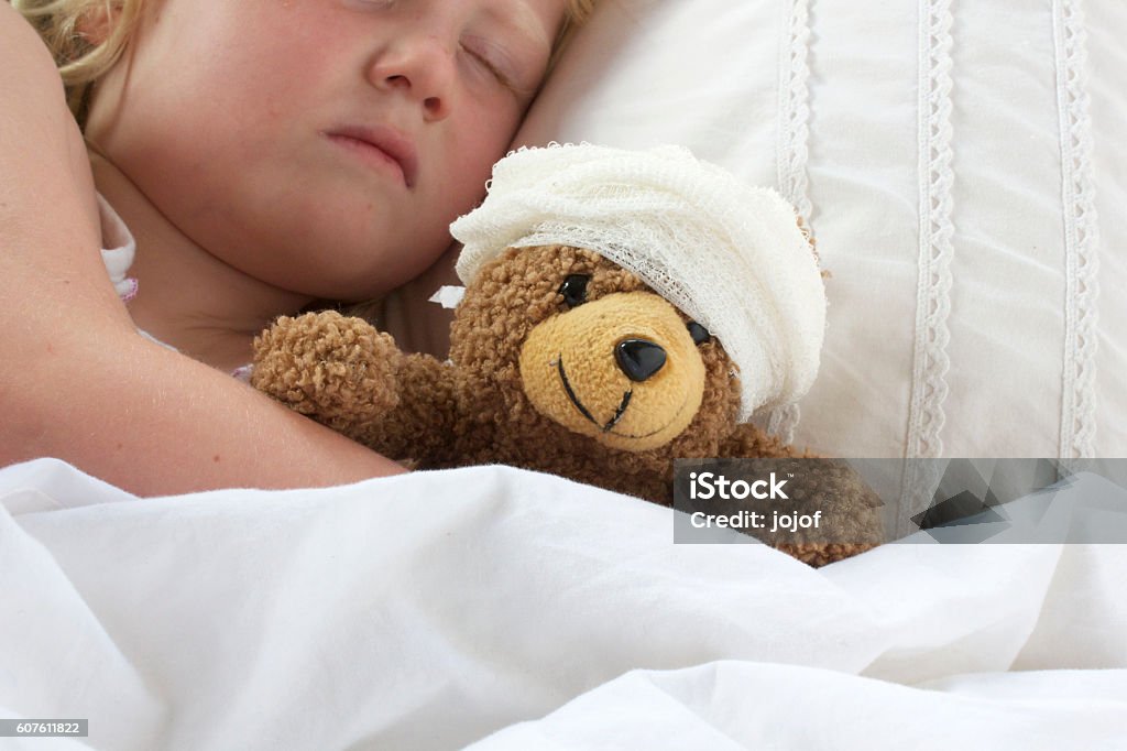 Chica en la cama abrazando un peluche con vendaje - Foto de stock de Venda libre de derechos
