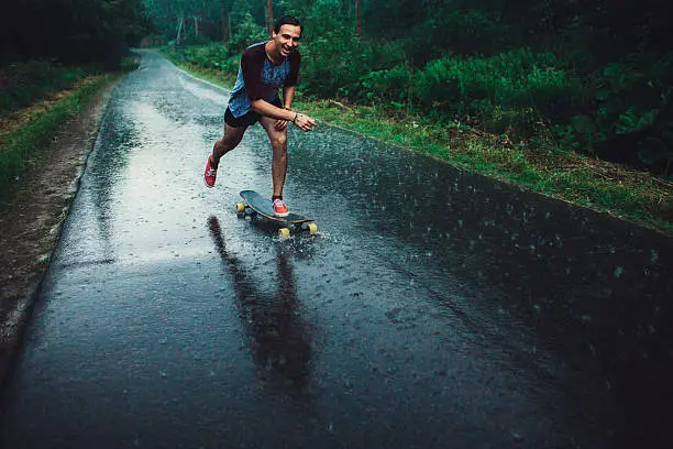 Young Caucasian man longboarding in forest 