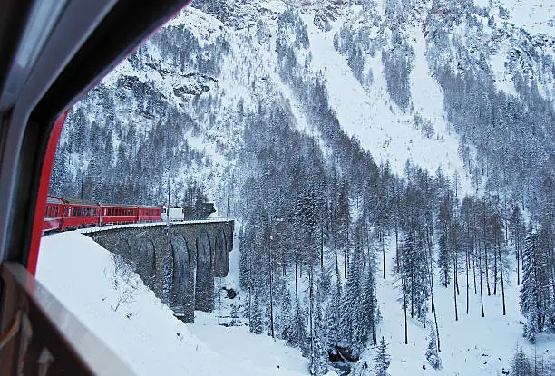 The Rhaetian Railway Express train from Chur to St. Moritz  on one of the many viaducts of the Albula line under cold winter conditions.