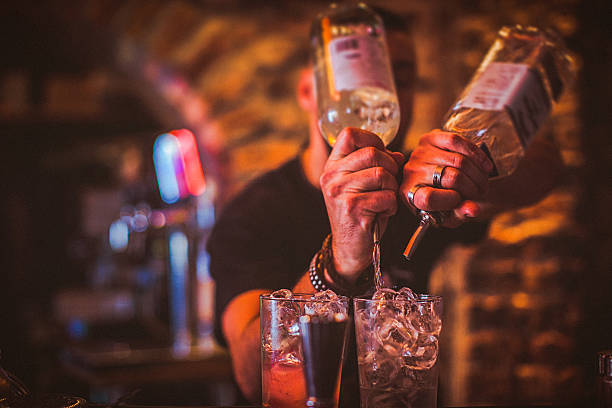 Midsection of young bartender preparing cocktails in nightlife bar