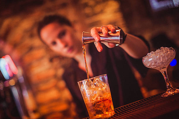 Midsection of young female bartender preparing cocktail in cocktail bar