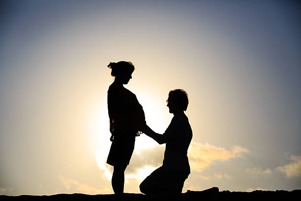 istock happy pregnant couple at sunset beach 607625654