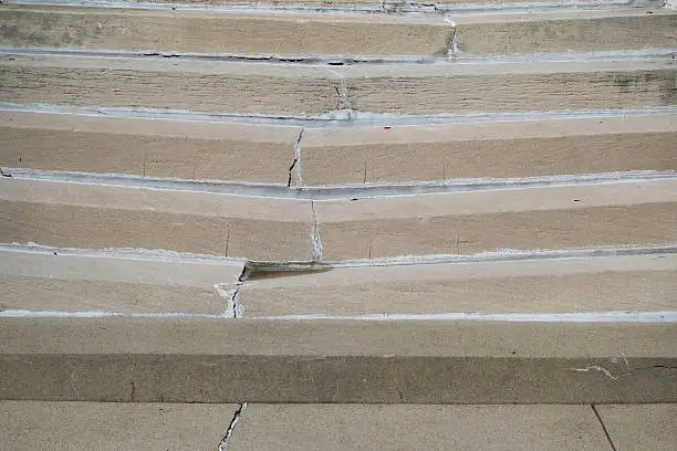 Cracked and broken cement steps with repairs, sunken in the middle, dangerous