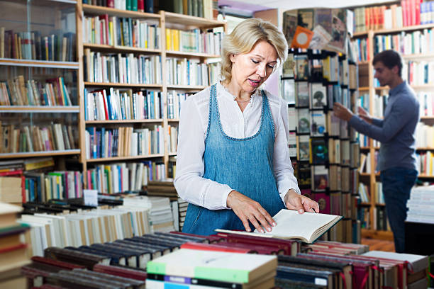 istock Positive mature female looking at open book in hands 607647512