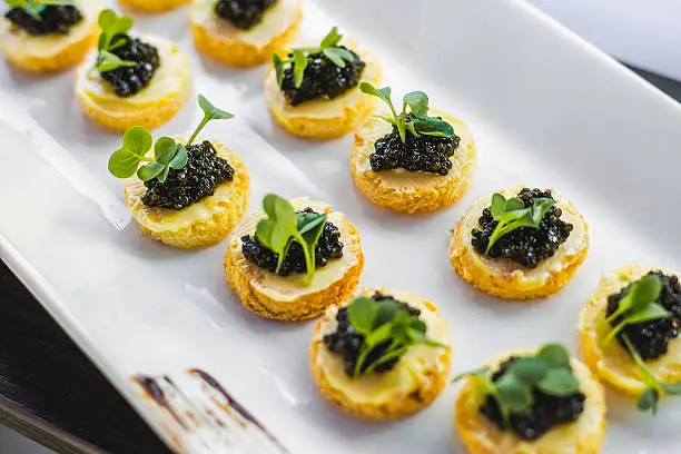 Sandwiches with black caviar on a white plate