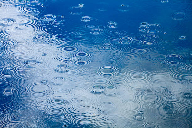 Rainy weather background Rain drops rippling in a puddle with blue sky reflection pond photos stock pictures, royalty-free photos & images