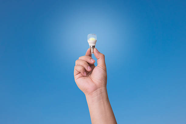 istock Hand holding LED Bulb with Lighting on blue sky background. 607653504