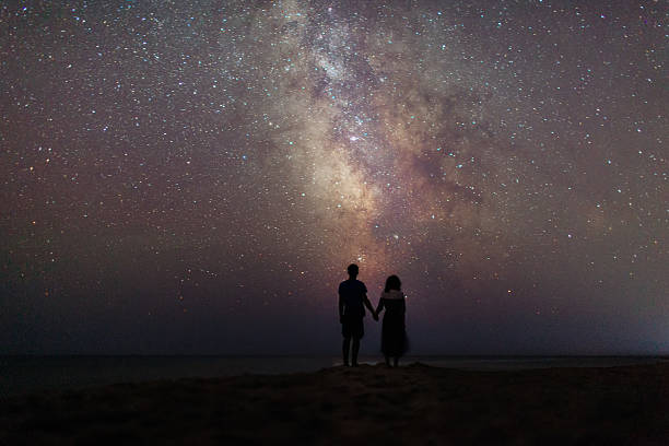 星空の下の海の近くのカップル - walking night men sunset ストックフォトと画像