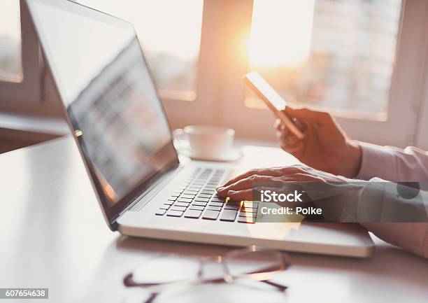 Lugar De Trabajo Hombre Usando Computadora Portátil Y Teléfono Inteligente Foto de stock y más banco de imágenes de Periodismo