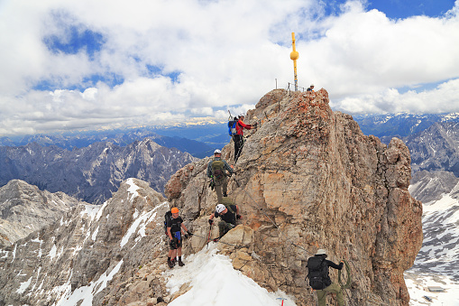 Zugspitze, Germany - June, 28, 2016: Hikers at the cross on the summit of Zugspitze Mountain, the highest in Germany.