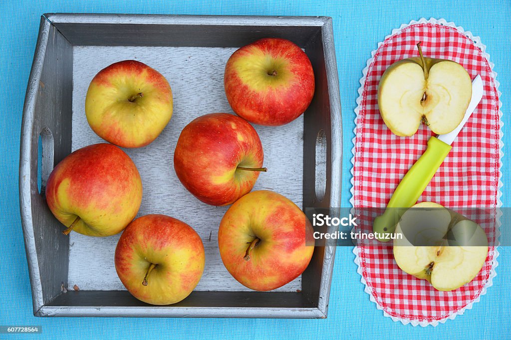 Red, yellow cut apples in wooden basket with green knife Red, yellow cut apples in traditional wooden basket and checkered napkin with green knife Apple - Fruit Stock Photo