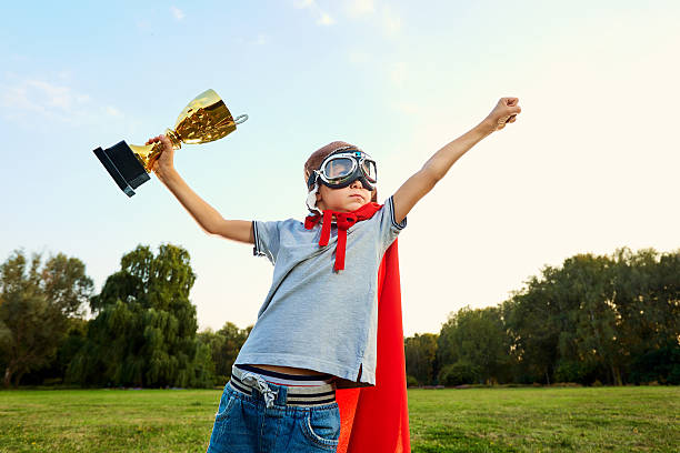istock Superhero boy with  championship trophy in hands on nature show 607729284