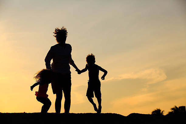 istock happy father with son and daughter jumping at sunset 607732320