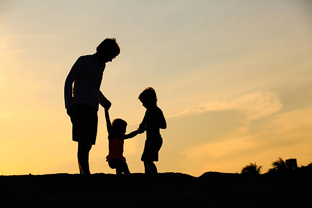istock father with son and daughter silhouettes play at sunset 607732648