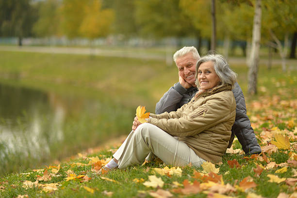 istock senior couple sitting near lake 607736048