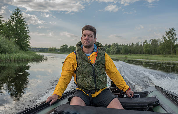 istock Brave handsome man is operating of boat on the river 607736612