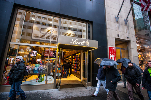 New York, USA  - December 29, 2013: People shopping in New York during winter holidays, USA. Lindt chocolate shop decorated for Xmas. 