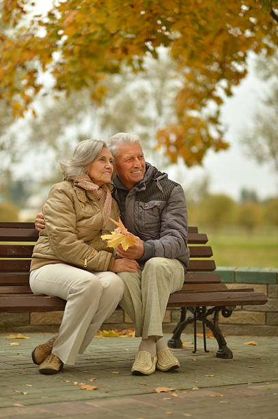 istock senior couple sitting on bench at park 607737638