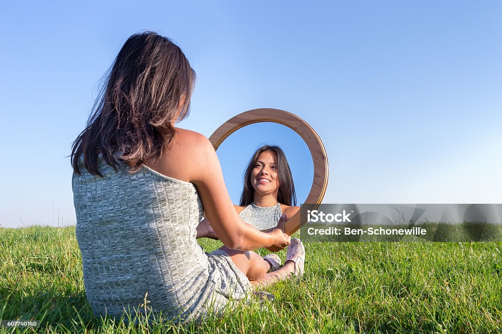 Mujer en la naturaleza viendo su imagen especular - Foto de stock de Espejo libre de derechos