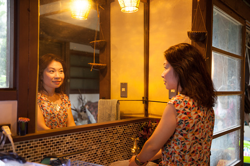 Japanese woman smiling at herself in the mirror