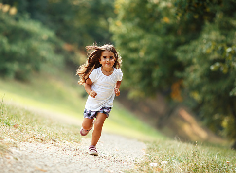 Little girl run through the park.