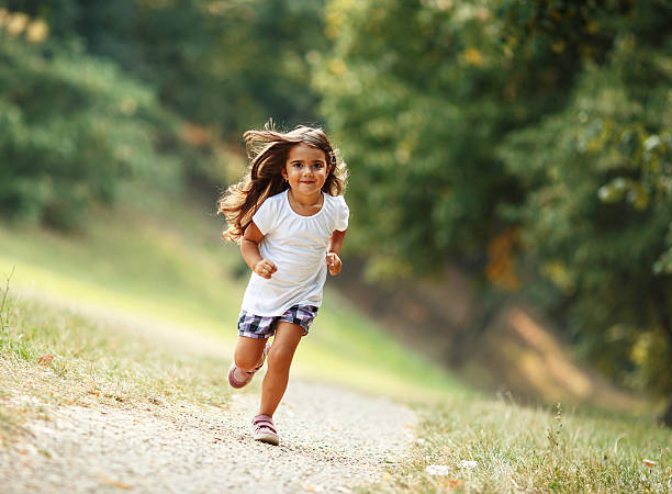 Little girl run through the park. stock photo