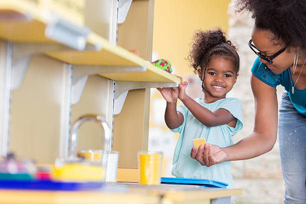 istock Adorable toddler girl using a play kitchen with her mom 607742594