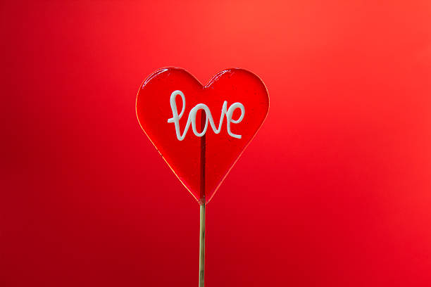 istock Single heart-shaped Lollipop with love sign on red background 607746436