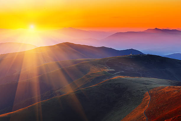 istock winding road through meadows of  mountain range at sunset 607748140