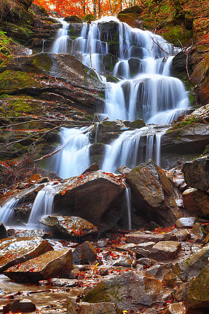 istock Beautiful waterfall in autumn forest 607748434