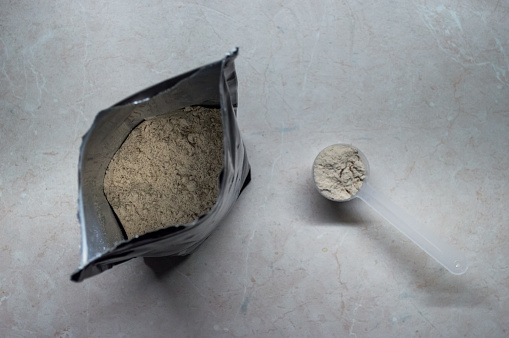 An overhead view of a bag of protein powder with a measuring scoop.