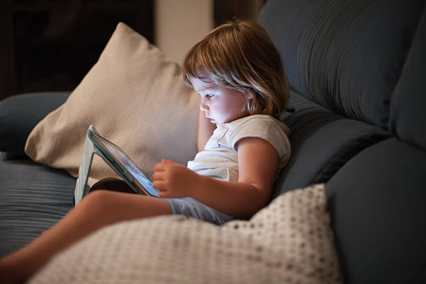 bambino seduto comodamente in divano a guardare tablet - comfortably foto e immagini stock