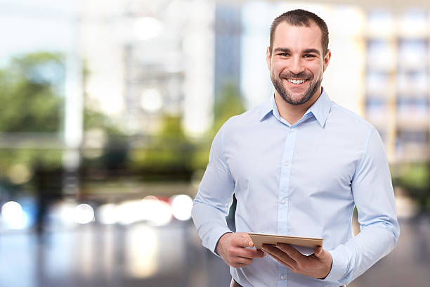 Man in office with tablet computer Portrait of professional business man in office with tablet computer button down shirt stock pictures, royalty-free photos & images